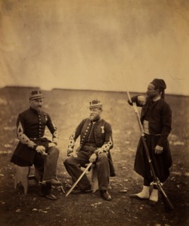 Two French officers, seated, and Zouave, standing with arm resting on rifle, Crimean War,