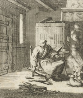 Writer William Shutter sitting on a low chair by the fire and picks up a few pieces of firewood,