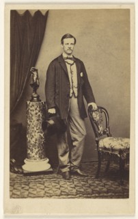 man with moustache standing, holding top hat in one hand, the other hand on chair back; F.W. Baker, British, active Calcutta