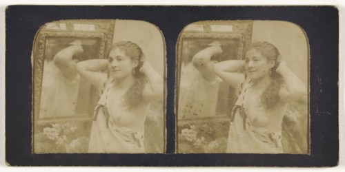 Woman before mirror with hands behind head, one breast exposed; French; 1855 - 1860; Hand-colored Albumen silver print