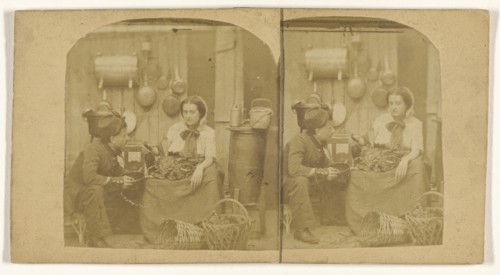 Woman seated in kitchen with foodstuffs on her lap, pouring wine into a pot being held by a man wearing a hat; French