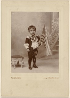 Little boy standing, holding an American flag; MacIntire, American, active 1890s, about 1890; Gelatin silver print
