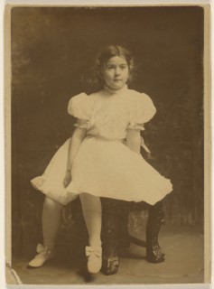 young girl in a white dress, seated; about 1920; Bromide print