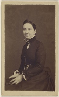 woman wearing a dark dress, holding a book, seated; 1865 - 1870; Albumen silver print