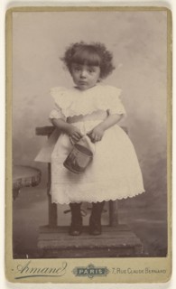 little girl standing in a chair, holding a pail with a ship on it; Armand; 1885 - 1895; Gelatin silver print