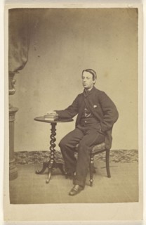 young man seated at a table with one hand on books; A. Crowe, British, active 1860s - 1870s, about 1865; Albumen silver print