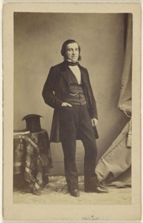 man standing with his hand in his pocket, a top hat on a table nearby; French; 1862; Albumen silver print