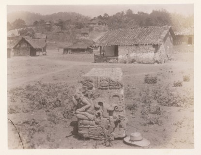 Carved block with hat in foreground and village behind, Edmund Lincoln miscellaneous papers relating to the excavation of Maya