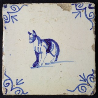 Animal tile, standing dog to the left with strange legs, in blue on white, corner motif ox's head, wall tile tile sculpture