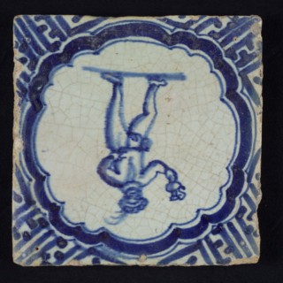 Figure tile, blue with standing man with beret and plume, with bird and jug in the hand, scalloped frame with braces, corner