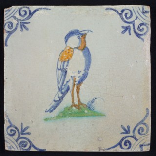 Animal tile, bird with on ground to the right in orange, yellow, green and blue on white, corner pattern ox head, wall tile