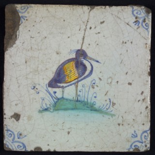 Animal tile, bird on piece of land to the right in yellow, orange, green and blue on white, corner pattern ossenkop, wall tile