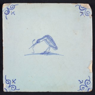 Animal tile, bird with long fish in its beak to the left, blue on white, corner motif ox's head, wall tile tile sculpture