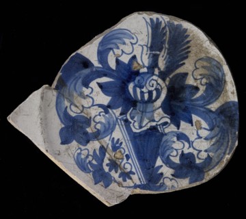 Fragment majolica dish, blue on white, heraldic image, helmeted coat of arms with diagonal distribution, above dark, under light