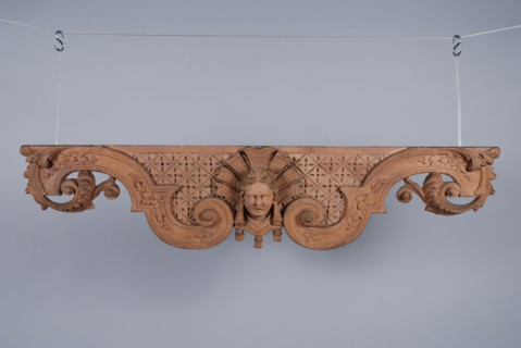Carved and painted wooden hanging ornament with woman's head in the middle, ornament wood carving sculpture visual material wood