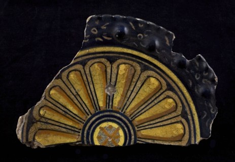 Fragment majolica plate, yellow, orange, dark blue (black?) On white, middle concentric circles, surrounded by broad nissenrand
