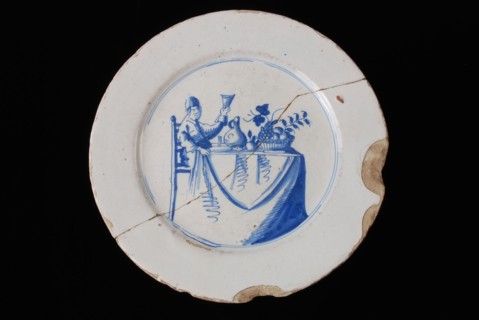 Faience plate on stand, blue on white, man with raised glass on covered table, plate crockery holder soil find ceramic