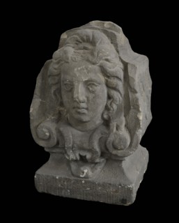 Basement, female head with curly hair on front, cross-shaped band decoration on sides, basement ornament building component