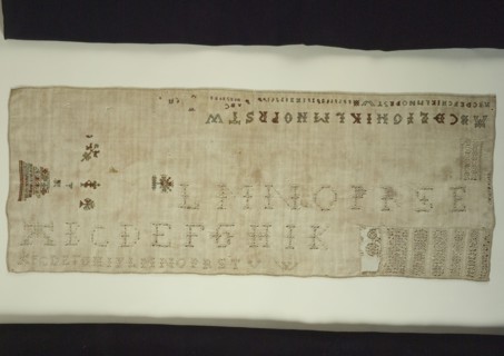 Sampler or lettercloth worked in colored silk and natural linen on cream colored linen in cross stitch and reticella
