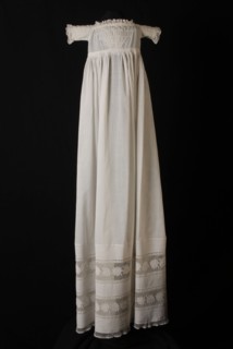 Long christening dress of fine white cotton, square neckline, bodice with smocking, hem edge with white embroidery and tulle