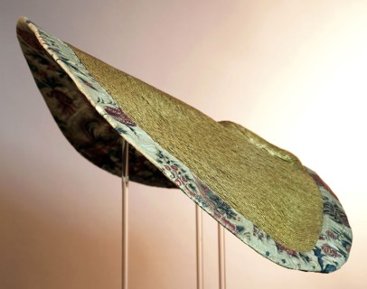 Large semi-circular sun hat, natural colored ribbon straw, low flat ball, very wide rim, lining of chintz and edge of pleated