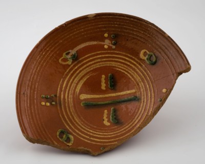 Red earthenware plate with simple silt decor of circles and stripes in yellow and green, plate dish crockery holder soil find