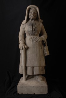 Simon Miedema, Image of old woman 'Kaatje', with walking stick, apron and book, façade sculpture sculpture footage building