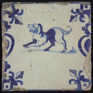 Animal tile, jumping dog to the left on plot between balusters, in blue on white, corner pattern French lily, wall tile