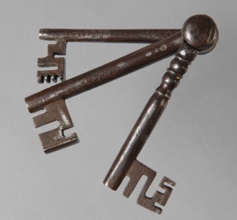 Three different iron keys, consisting of key stems with beards, which are hinged to each other at the top of the handle, key