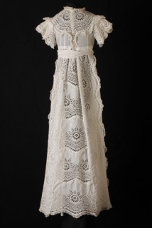 Long wide baby dress in white cotton, front, over sleeves and wide front on the skirt of coarse embroidery with large wheel