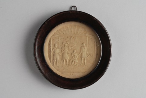 Small circular relief plaque in wooden frame, with historical representation of four people and child in room, plaque embossed