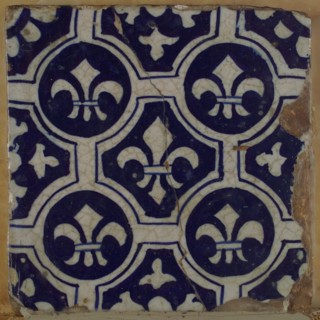 Two-tone tile, blue on white background, four circles with white French lily around central ornament with lily, wall tile