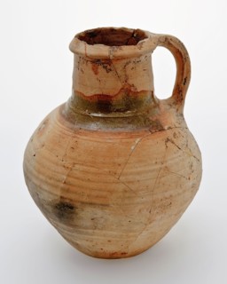 Pottery jug on lens bottom, yellowish shard, green lead glaze on the shoulder, jug crockery holder soil find ceramic earthenware