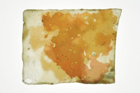 Fragment of small pane, green tinted window glass partially covered with thick layer of irisation, window glass building