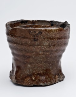 Bottom of stoneware drinking jug or cup on pinched foot, brown salt glaze, drinking jug cup fragment tableware holder soil find