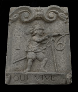 Wall brick from gate with musketeer and ribbon with text qui vive 16, facing stone sculpture sculpture building component