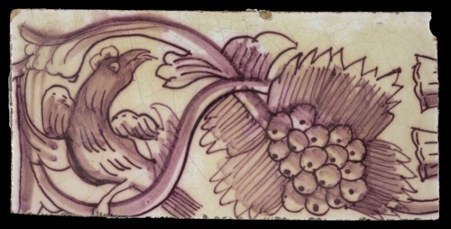 Rectangular edge tile in purple with serpentine decor of leafy tendril, twisted bird to the right, grape bunch, border tile wall