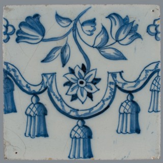Border tile, blue on white, garland with tassels, above which flower tendril with two tulips and other flower, vertically