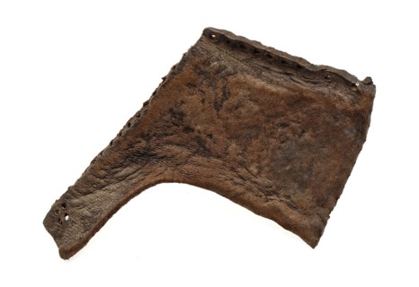 Side piece of leather shoe with sewing holes along edges, shoe footwear clothing fragment soil finding leather, archeology