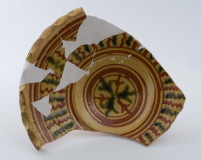 Earthenware dish on stand with wavy saucer edge, clear sludge decoration in yellow and green, dish plate crockery holder soil