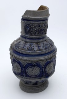 Stoneware jug with around belly arcade with portrait medallions, ear with pinched tail, cylindrical neck, jug crockery holder