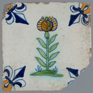 Tile, flower on ground in yellow, green and blue on white, corner pattern french lily, corner point yellow, wall tile