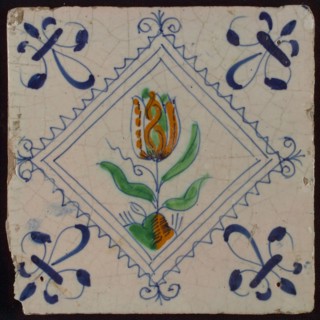 Tile, tulip on ground in orange, green and blue on white, inside serrated square with plume, corner pattern french lily, wall