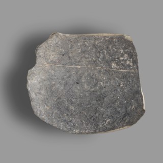 Fragment of a bucchero nero bowl with a flat bowl and a ring-shaped stem. On the inside of the bowl