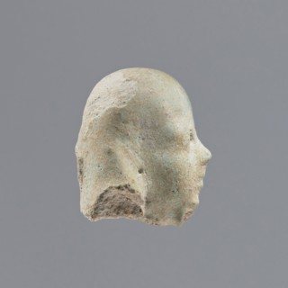 Fragment of a shabti, heads, grave goods, wigs. Head of a shabti figurine with indistinct facial