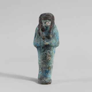 Ushabti, Mummy-shaped figurine. Hands folded on the chest—right over left. Hoes in each hand. Large