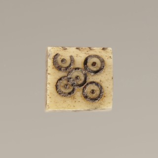 Game die made of animal bone with six unequal sides. Each side is engraved with a number from 1 to