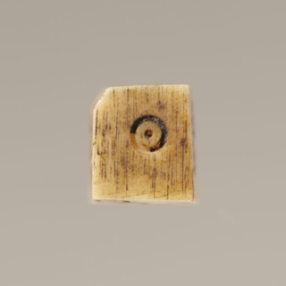 Game die made of animal bone with six unequal sides. Each side is engraved with a number from 1 to