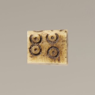 Game die made of animal bone with six unequal sides. Each side is engraved with a number from 1 to