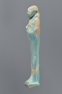 Ushabti, mummy-shaped figurine. Standing on a base with a flat pillar at the back. Arms folded